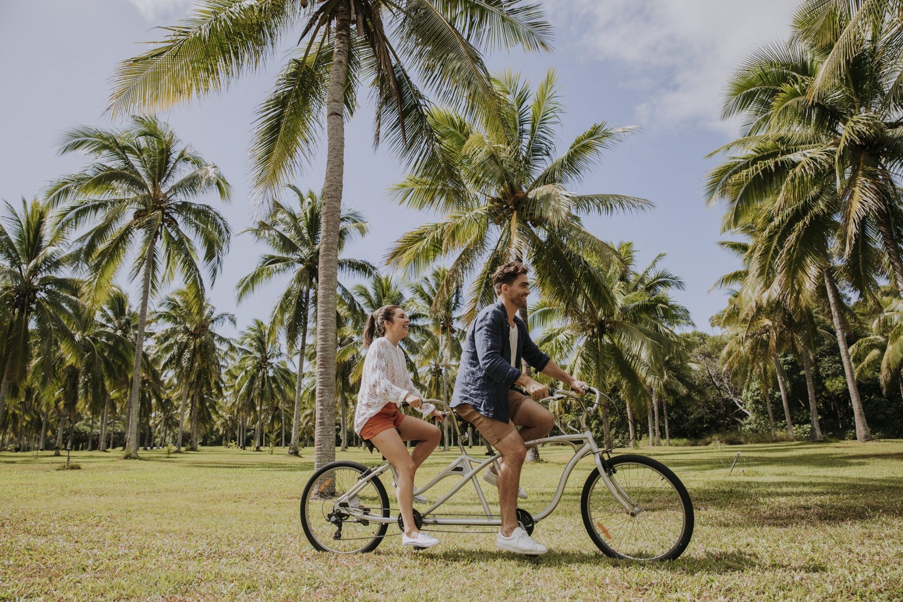 Girl boy riding through coconut palms